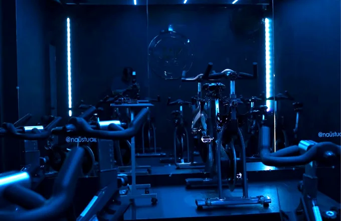 Salón de indoor cycling de Naü Studio con iluminación neón